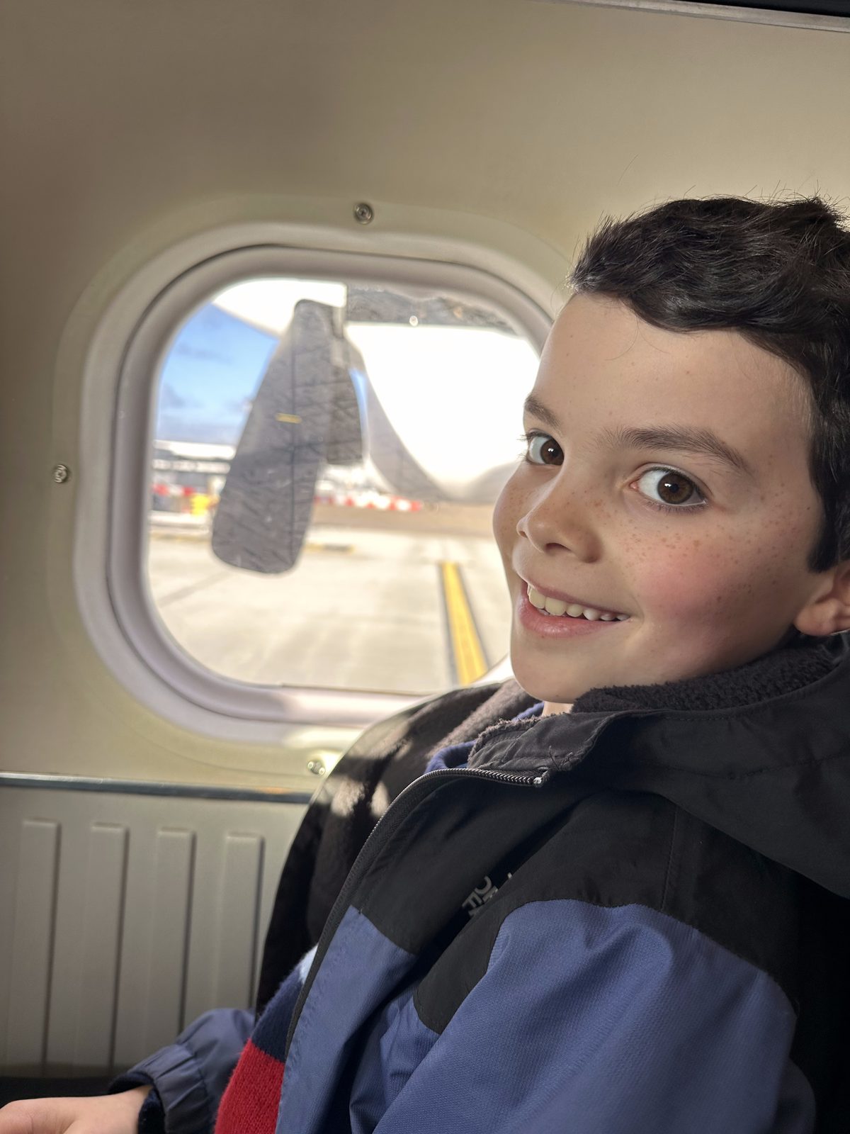 Keir on a plane, looking out at another aircraft on the runway.